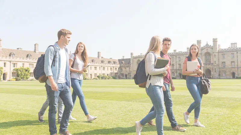 Students walking across a university campus lawn